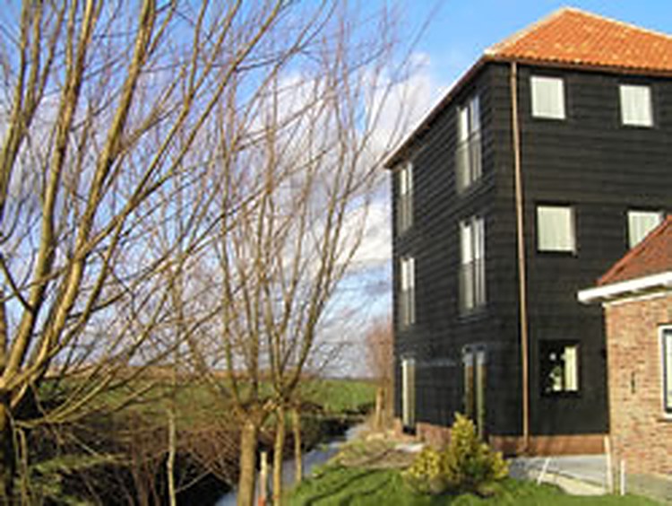 De gerestaureerde hooiberg van Hoeve Meerzicht met donker houten gevel, waarin de gastenkamers zijn gemaakt